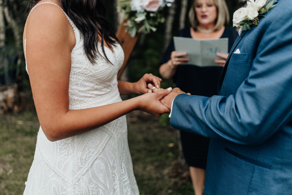 bride and groom exchanging rings during intimate backyard wedding ceremony