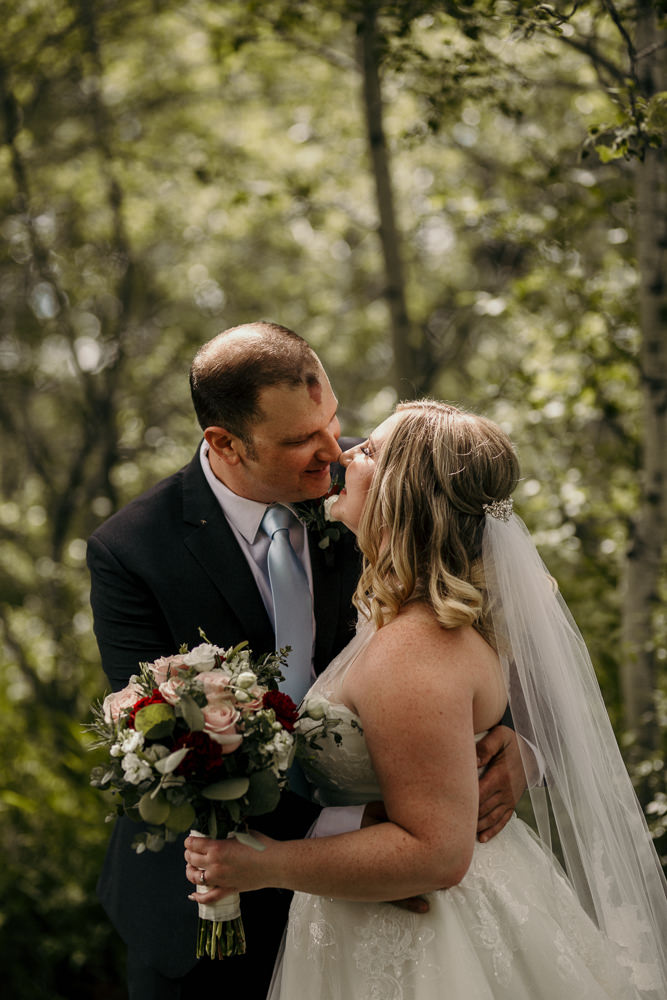 bride and groom in forest holding bouquet
