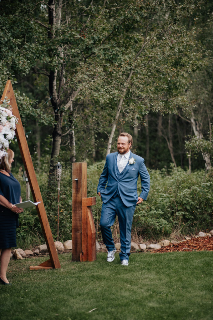 groom in blue suit at altar before backyard wedding ceremony