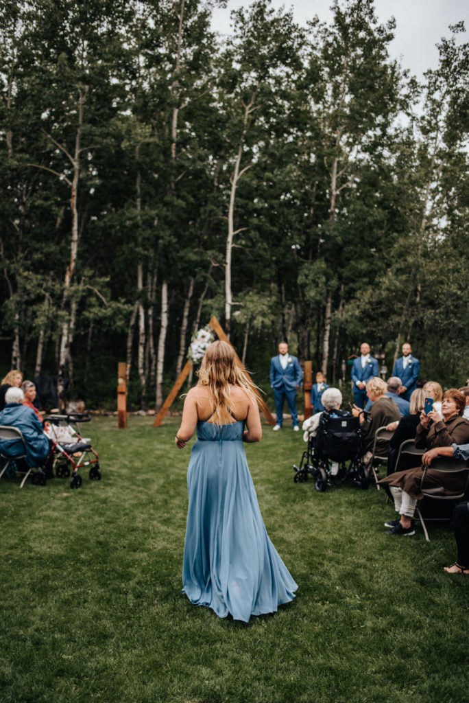 bridesmaid in blue dress entering backyard wedding ceremony